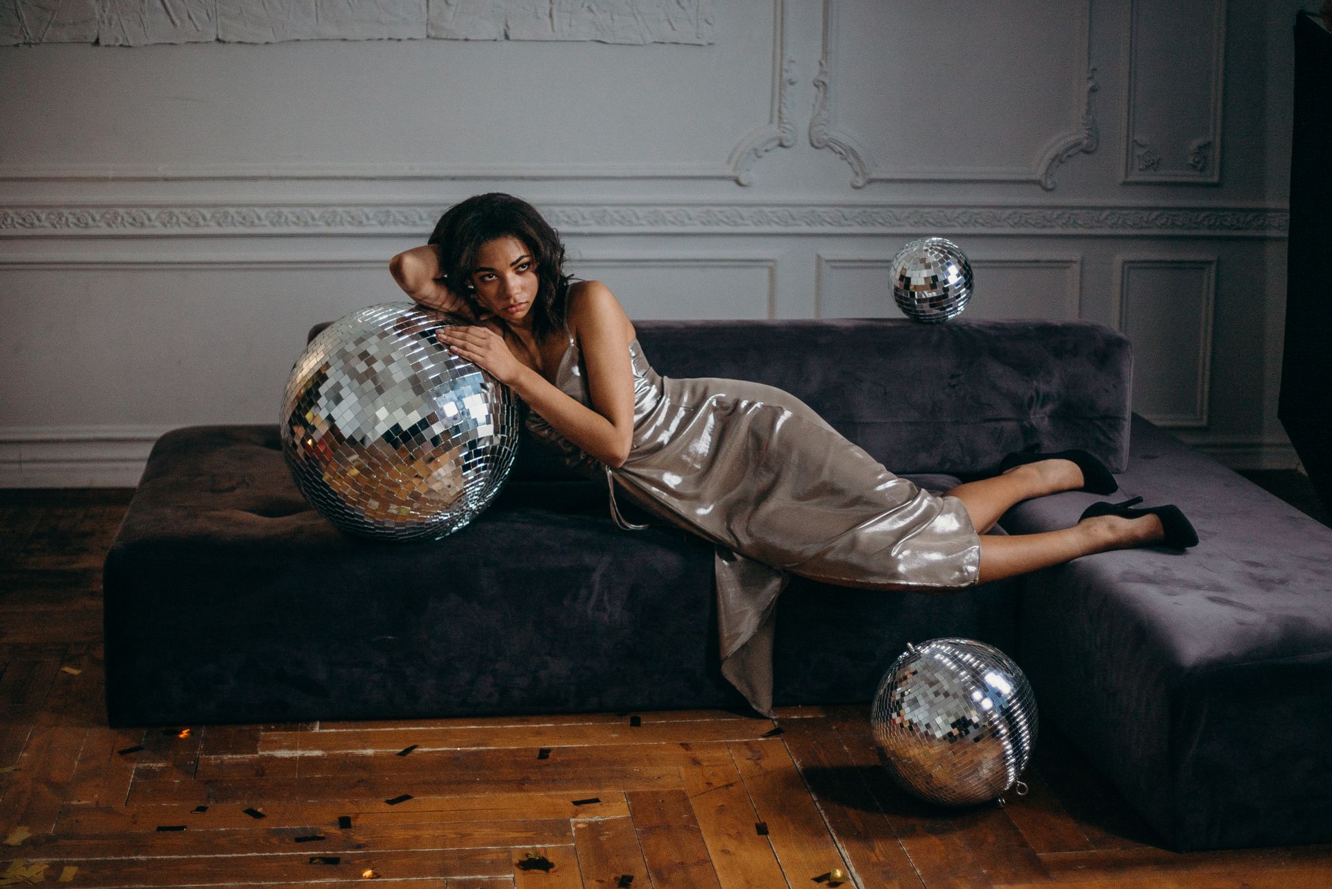 Model in a champagne gown reclining among mirror balls